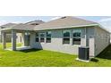 A backyard features a covered patio adjacent to a house with large windows and simple landscaping at 1163 James Paul Rd, Davenport, FL 33837