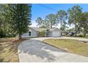 Landscaped single-story home with mature trees and a curved driveway leading to an attached two-car garage at 131 Autumn Ct, St Cloud, FL 34771