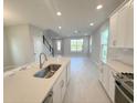 Open-concept kitchen with a view of the living area, featuring an island, stainless steel appliances, and ample lighting at 1360 Twelve Oaks Rd, St Cloud, FL 34771