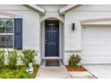 Close-up of front door and welcome mat, with blue shutters and manicured landscaping at 149 Hickory Course Cir, Ocala, FL 34472
