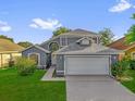Inviting gray two-story home with a lush green lawn and a two-car garage at 1851 Wimbledon St, Kissimmee, FL 34743
