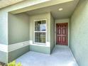 View of a front porch that has a large brown front door and white trimmed window at 284 Talladega Ln, Polk City, FL 33868