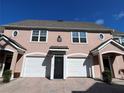 Inviting townhome exterior featuring a pink facade, arched garage entrance, and neat landscaping at 3337 Soho St # 205, Orlando, FL 32835