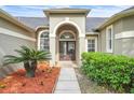 Inviting front entrance with double doors, arched transom window, and lush landscaping at 339 Hammock Dunes Pl, Orlando, FL 32828