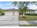 Charming single-Gathering home featuring a three-car garage, landscaped yard, and mature trees at 339 Hammock Dunes Pl, Orlando, FL 32828