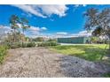 Property with gravel parking, lawn and large metal barn with beautiful skies in the background at 4640 Hickory Tree Rd, St Cloud, FL 34772