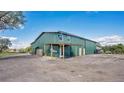 Large, green metal barn with an overhanging porch area and ample parking, perfect for various uses at 4640 Hickory Tree Rd, St Cloud, FL 34772