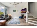 A stylish living room features a cozy couch, TV, modern ceiling fan, and stairway with wood floors at 6672 S Goldenrod Rd # 132B, Orlando, FL 32822