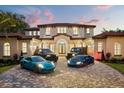 Stunning front exterior of home showcasing four luxury vehicles on a brick driveway at 11019 Kentmere Ct, Windermere, FL 34786