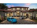 Stunning two-story home with red tile roof, arched windows, grand entrance, and two sports cars in the brick driveway at 11019 Kentmere Ct, Windermere, FL 34786