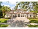 Elegant two-story home features a red tile roof, large brick driveway, and manicured landscaping at 11019 Kentmere Ct, Windermere, FL 34786