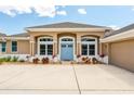 Inviting home featuring a blue front door, arched windows, and a well-maintained front yard with vibrant plants at 13111 Meergate Cir, Orlando, FL 32837