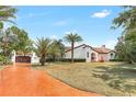 Stunning exterior view of Spanish-style home featuring a terracotta roof, palm trees, and a brick driveway at 13124 Filly Ct, Windermere, FL 34786