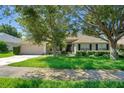 Charming single-story home with lush green lawn and mature trees on a sunny day at 1375 Willow Wind Dr, Clermont, FL 34711