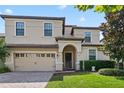 Inviting two-story home features an arched entryway, neat landscaping, and a convenient two-car garage at 1425 Thunderbird Rd, Davenport, FL 33896