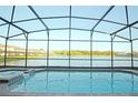 Screened-in pool with lake view and a hot tub surrounded by brick pavers, perfect for relaxation at 1663 Lima Ave, Kissimmee, FL 34747