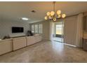 Comfortable living room with large windows and sliding glass doors to a patio and modern light fixture at 18219 Oliver Twist Way, Winter Garden, FL 34787