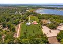 Aerial view of a large, fenced property featuring a home, additional buildings, mature trees and lake views at 36408 E Eldorado Lake Dr, Eustis, FL 32736