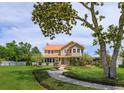 Two-story home with copper roof, lush front yard, mature trees, a fountain and a winding walkway at 36408 E Eldorado Lake Dr, Eustis, FL 32736