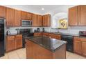 Well-equipped kitchen featuring wood cabinetry, black appliances, granite countertops and a central island at 411 Cabello Dr, Davenport, FL 33837