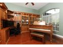 Dedicated office with custom built-in shelving, desk area, and a vintage grand piano at 753 Grey Heron Pl, Chuluota, FL 32766