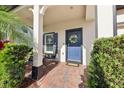 Inviting front porch with blue door, wreath, seating area, and manicured hedges at 10404 Park Commons Dr, Orlando, FL 32832