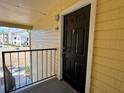 Apartment entryway with a black front door, showing the exterior yellow siding and a partial view of the complex at 1081 S Hiawassee Rd # 726, Orlando, FL 32835