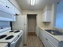Galley kitchen with white cabinets, appliances and a laundry closet with washer and dryer hookups at 1081 S Hiawassee Rd # 726, Orlando, FL 32835