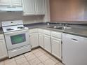 Efficient kitchen featuring white cabinets, stove, dishwasher and tile flooring at 14001 Fairway Island Dr # 513, Orlando, FL 32837