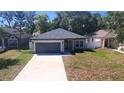 Charming single-story home featuring a gray exterior, a two-car garage, and a well-maintained front yard at 1412 Pine St, Orlando, FL 32824