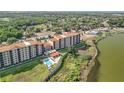 Aerial view showcasing the condo complex with a pool, parking, landscaping, and lakeside setting at 16300 County Road 455 # 405, Montverde, FL 34756