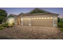 Home exterior showcasing a spacious three-car garage with a brick paved driveway and manicured landscaping at 2086 Biller Cir, The Villages, FL 32163