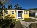 Welcoming blue front door of the cheerful yellow house, framed by white pillars and landscaping at 5216 Davisson Ave, Orlando, FL 32810