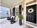 Cozy front porch featuring stylish black rocking chairs and a decorative wreath on the front door at 616 Nadina Pl, Celebration, FL 34747