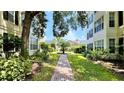 A brick pathway through a landscaped courtyard with trees, lawn, and colorful plantings and a palm tree centerpiece at 921 Begonia Rd # 302, Celebration, FL 34747