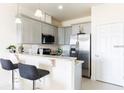Stylish kitchen featuring gray cabinets, granite countertops, modern appliances, and a breakfast bar with seating at 1798 Coriander Dr, Kissimmee, FL 34759
