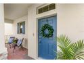 Home's entrance with a blue door, a wreath, and an inviting covered porch with chairs at 17985 Adrift Rd, Winter Garden, FL 34787