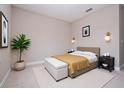 A bright bedroom with tan walls, neutral carpet, side tables, and a padded bench at the foot of the bed at 2041 Warrens Ave, Maitland, FL 32751
