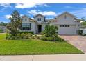 Inviting home featuring lush landscaping, a brick driveway, and a convenient attached two-car garage at 4296 Mirror Ct, Clermont, FL 34714