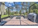 Relaxing screened-in patio with brick flooring, a built-in fire pit, and an outdoor kitchen area at 8768 Sonoma Coast Dr, Winter Garden, FL 34787