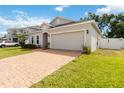 Well maintained single-story home with brick driveway, two car garage, landscaped yard and white vinyl fence at 928 Avenal Ln, Davenport, FL 33837