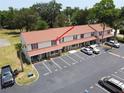 Aerial view of condo complex with parking, mature trees, and building painted in neutral color with red shutters at 980 Canal View Blvd # N2, Port Orange, FL 32129