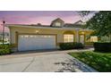 Inviting home with a two-car garage, well-maintained lawn, and a welcoming entrance at sunset at 13241 Fountainbleau Dr, Clermont, FL 34711