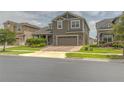 Inviting two-story home featuring a well-manicured lawn and a brick paved driveway leading to a two car garage at 3302 Stonegate Dr, Ocoee, FL 34761