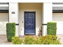 Inviting townhome entrance with a blue front door, brick walkway, and manicured shrubs at 10374 Park Commons Dr, Orlando, FL 32832