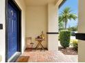 Cozy front porch with brick pavers, small table, and a view of lush greenery and palm trees at 10374 Park Commons Dr, Orlando, FL 32832