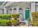 Inviting front porch features a rocking chair and a vibrant green door, complemented by lush shrubbery at 288 Englenook Dr, Debary, FL 32713