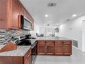 Open-concept kitchen with stainless steel appliances, mosaic backsplash and granite countertop bar seating area at 3120 Ginger Cir, Orlando, FL 32826