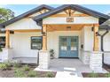 Inviting front porch with stone columns, wooden beams, and a stylish blue double door with transom windows at 40 W Laurel St, Apopka, FL 32703
