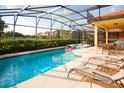 Stunning screened-in pool and spa with lounge chairs, offering a private outdoor oasis at 4405 Acorn Ct, Davenport, FL 33837